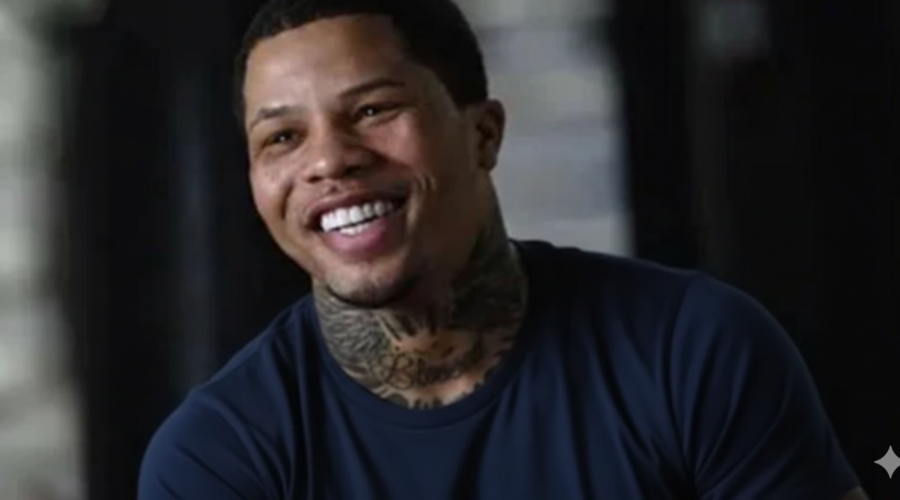 Smiling professional boxer with neck tattoos wearing a dark blue shirt, captured during an interview in an indoor setting.
