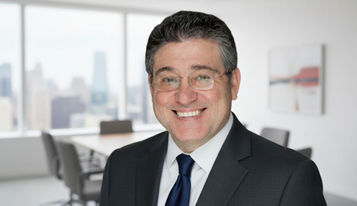 Smiling businessman in formal suit standing in a modern office with city view background