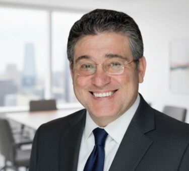 Smiling businessman in formal suit standing in a modern office with city view background